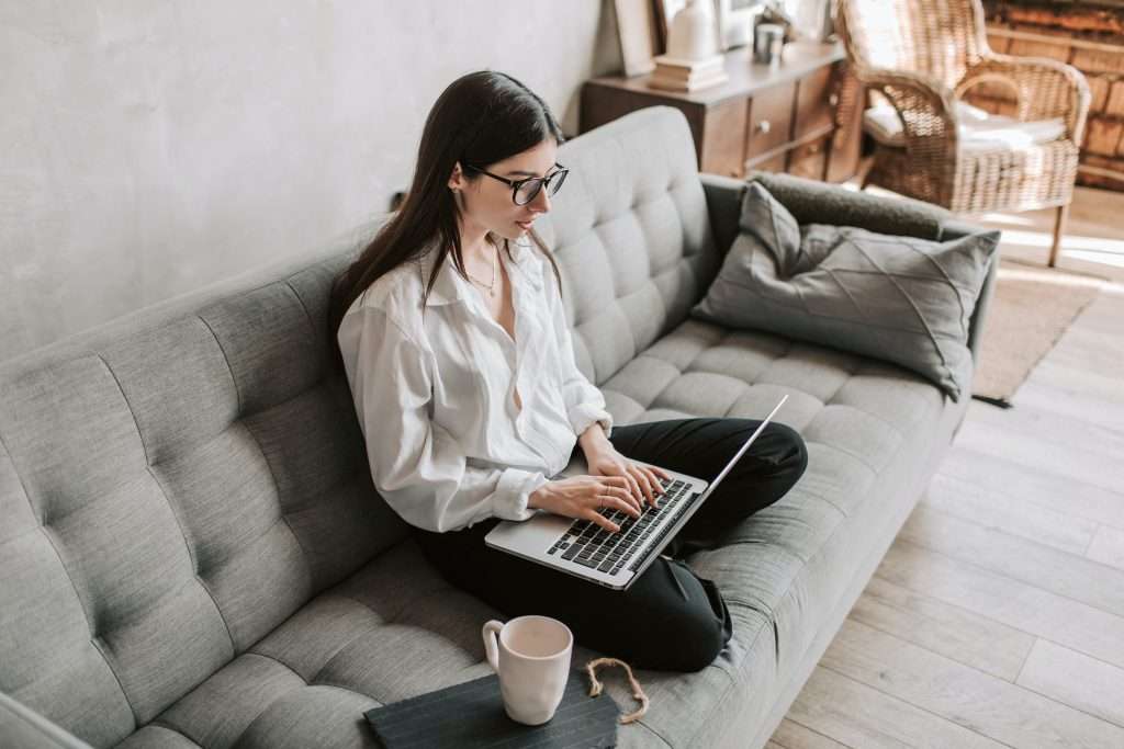 girl on grey sofa using laptop