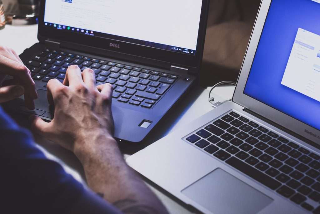 person using two laptops