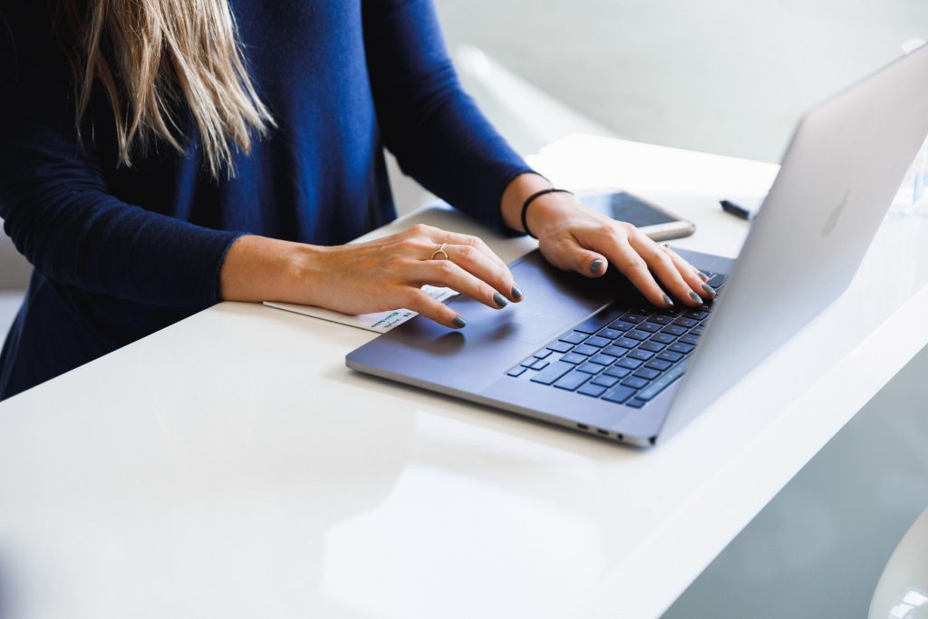 Woman in blue long sleeve shirt typing on laptop
